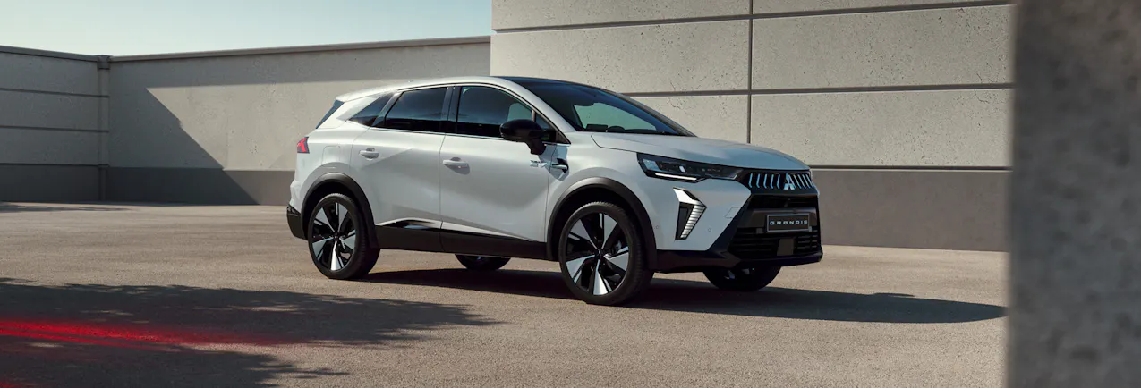 Mitsubishi Grandis blanche, avec un beau mur en béton en arrière-plan