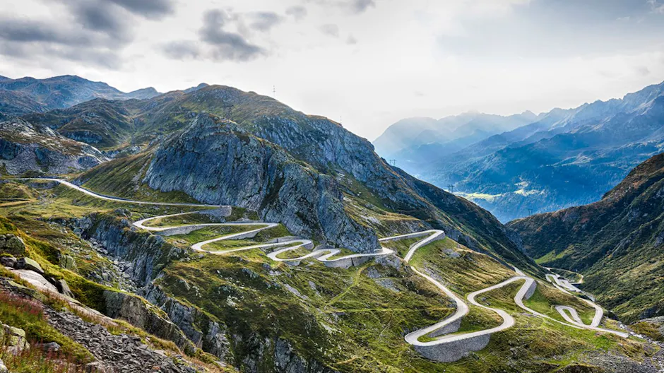 Kurvige Hochgebirgsstraße des San Bernardino Passes, umgeben von grünen Berghängen