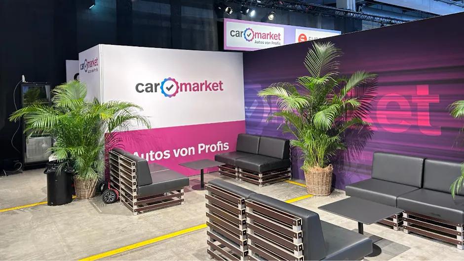 Area lounge con divani e piante allo stand Carmarket.