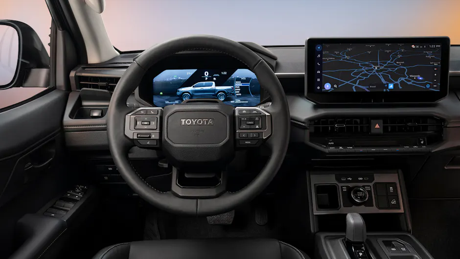 Innenraum des Toyota Hilux BEV mit digitalem Cockpit, Multifunktionslenkrad und zentralem Touchscreen mit Navigationsanzeige.