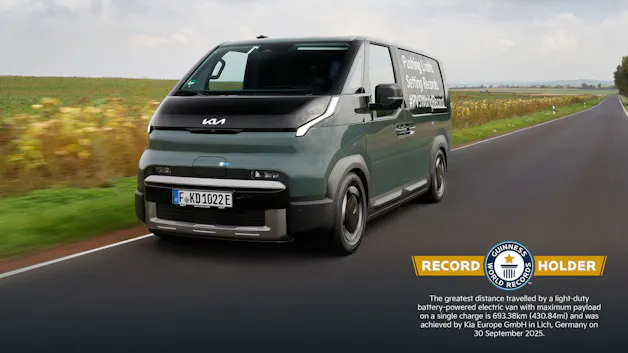 Kia PV5 Cargo fährt auf einer Landstrasse, seitlich beschriftet mit „Pushing Limits. Setting Records“