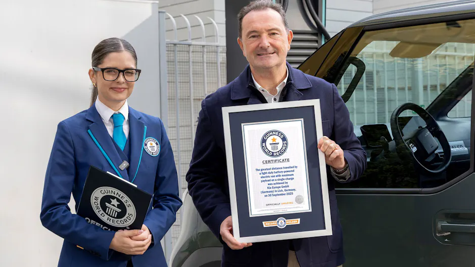 Zwei Personen stehen neben einem Kia PV5; eine Guinness-World-Records-Beamtin und ein Mann halten ein offizielles Rekordzertifikat.