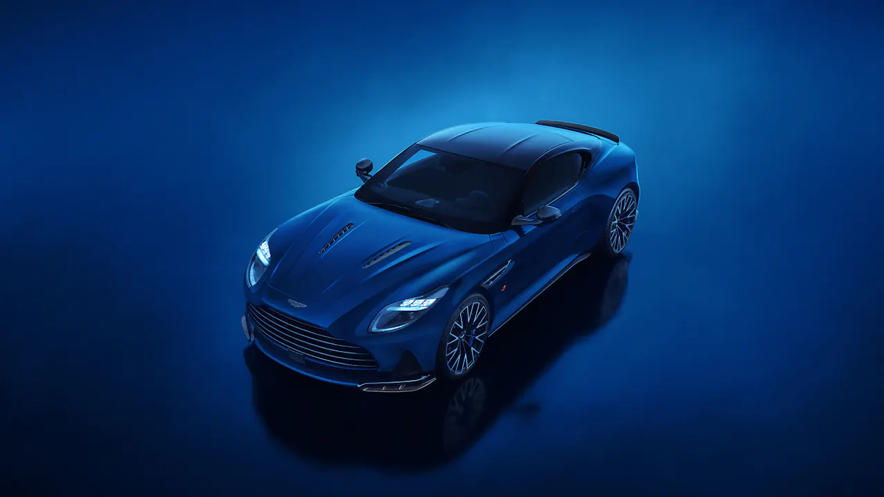 Aston Martin DB12 S in blauer Lackierung aus hoher schräger Perspektive vor blauem Hintergrund.