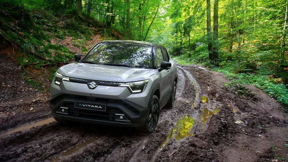 Suzuki e-Vitara su una strada boschiva fangosa.