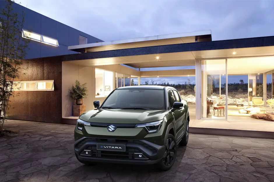 Suzuki E-Vitara in un elegante colore verde, davanti a una casa moderna