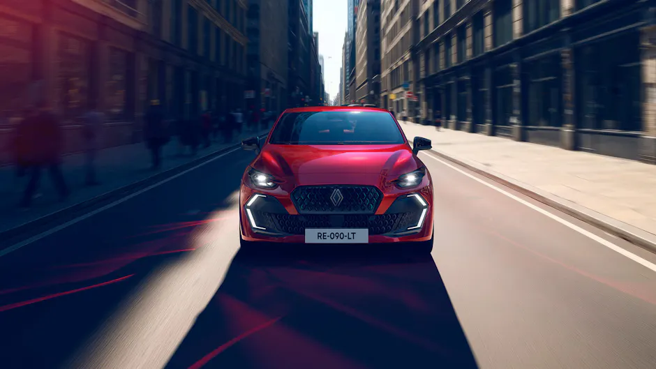 Roter Renault Clio frontal in urbaner Strasse, dynamische Fahrt.
