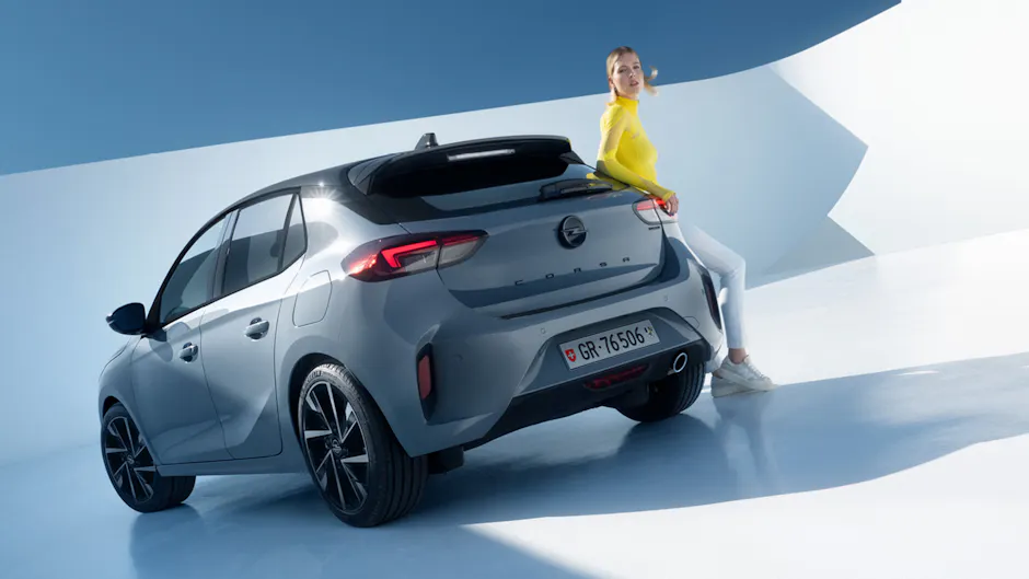 Opel Corsa, von Hinten, eine Frau lehnt sich an den Corsa
