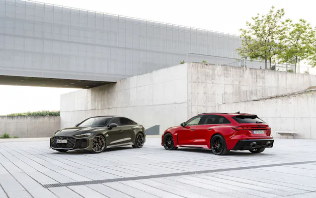 Neue Audi RS5 Baureihe in Grün und Rot, vor einem modernem Betongebäude