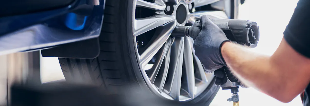 Un addetto dell'officina monta gli pneumatici sull'auto