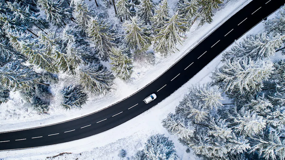 Une route enneigée entourée d'une forêt, vue d'en haut