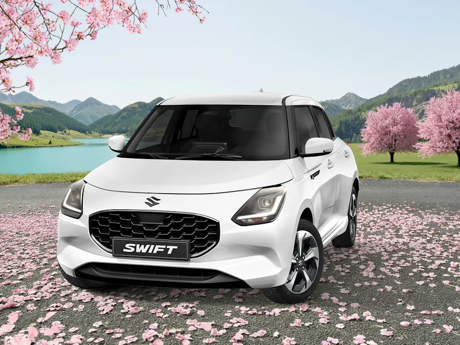 Suzuki Swift in Weiss unter einem pinken Sakurabaum, eine grüne Landschaft im Hintergrund