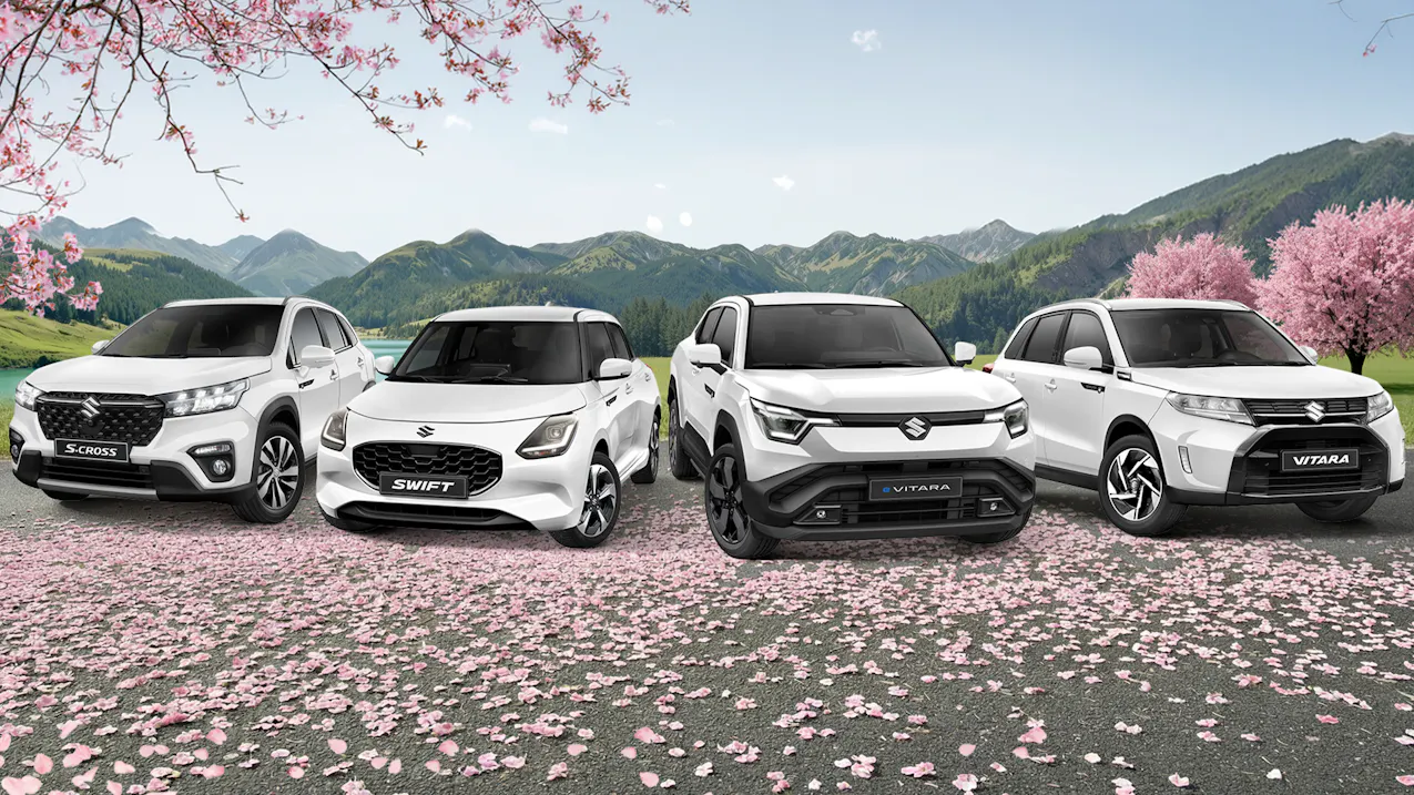 Suzuki Modellreihe in Weiss, unter pinken Sakurabäumen und eine grüne Landschaft im Hintergrund