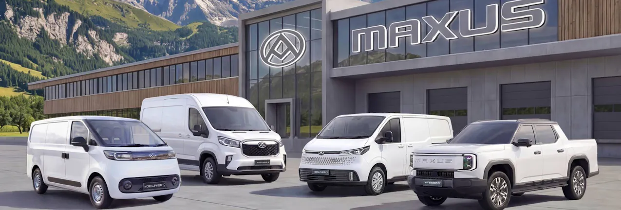 Modelli Maxus di colore bianco davanti a un negozio Maxus, con le montagne sullo sfondo