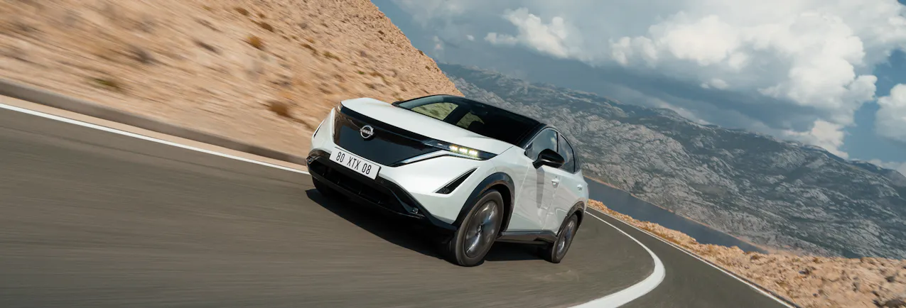 Ein weisser Nissan Ariya fährt in der Wüste
