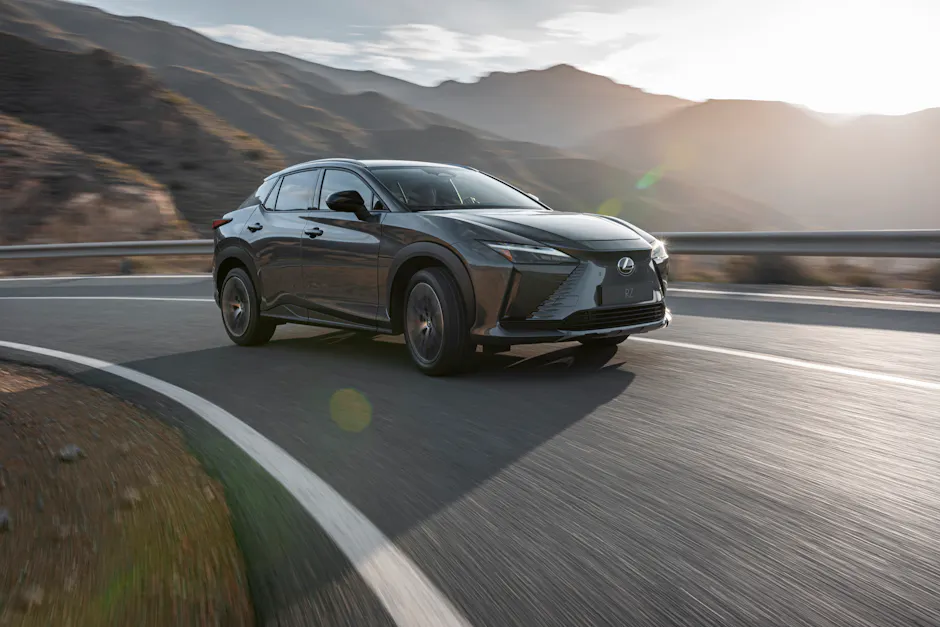 Lexus RZ fahrend in einer Kurve, Berglandschaft im Hintergrund