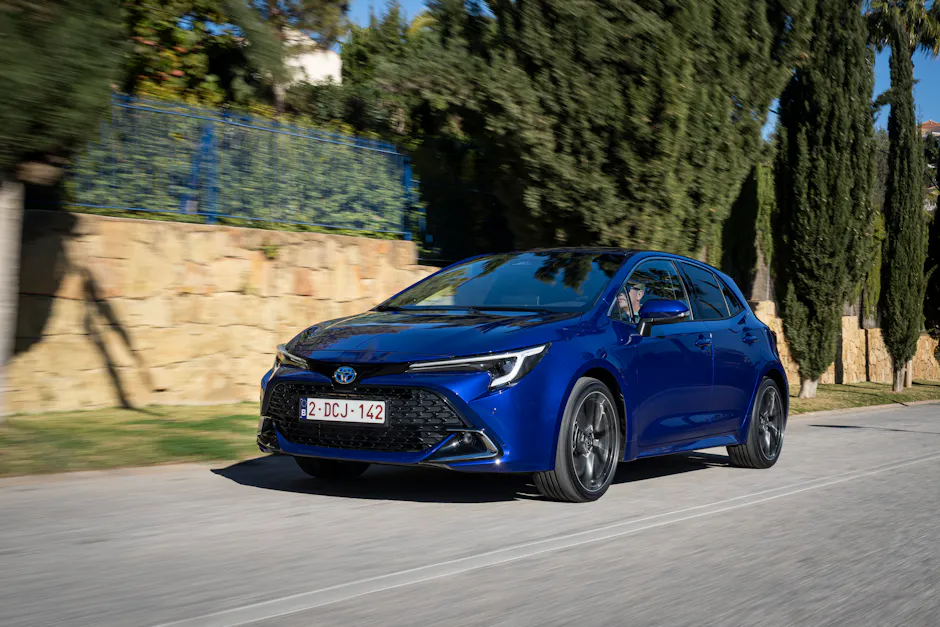 Toyota Corolla in Blau, Steinmauer und Bäume im Hintergrund